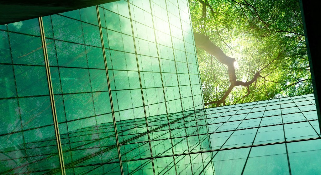 Modern glass building reflecting green trees — sustainable construction